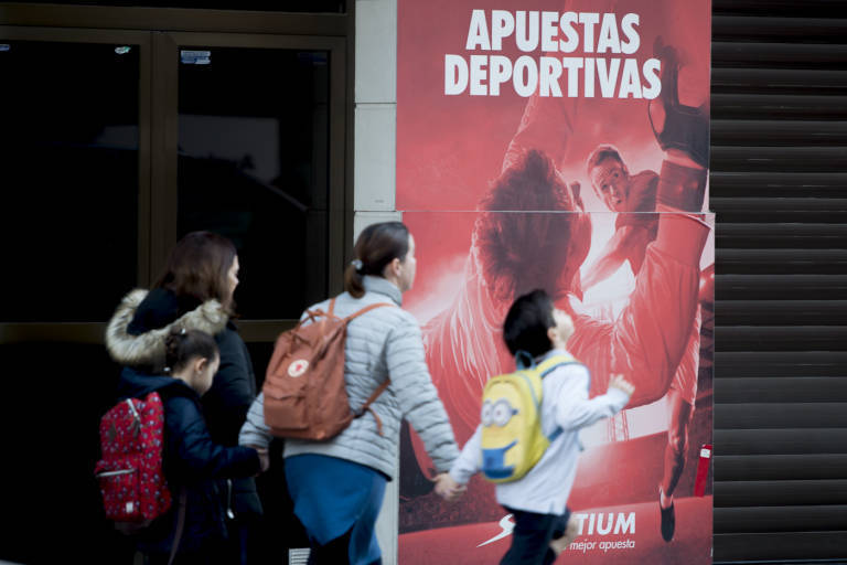 Una familia pasa por delante de un local de apuestas en València. Foto: KIKE TABERNER