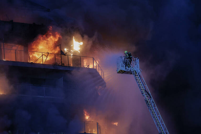 Bomberos durante su trabajo para apagar las llamas del edificio. Foto: EFE/MANUEL BRUQUE